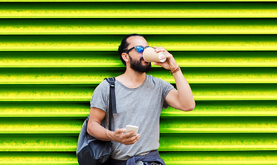 Image showing man with smartphone drinking coffee over wall