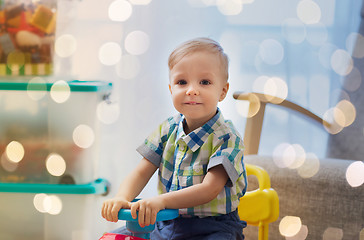 Image showing happy little baby boy driving ride-on car at home