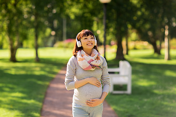 Image showing happy pregnant asian woman in headphones at park