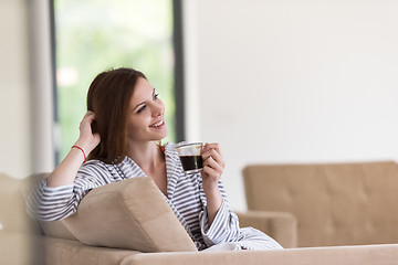 Image showing young woman in a bathrobe enjoying morning coffee