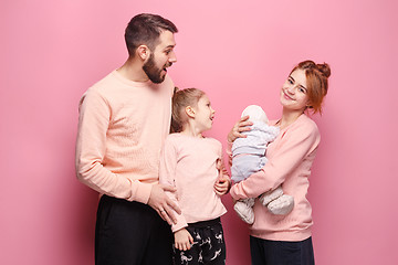 Image showing Surprised young family looking at camera on pink