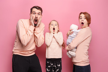 Image showing Surprised young family looking at camera on pink