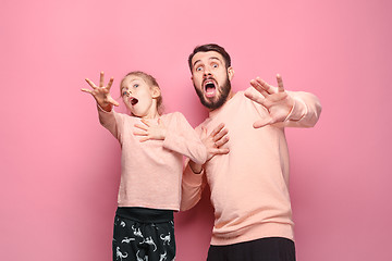 Image showing Surprised young family looking at camera on pink