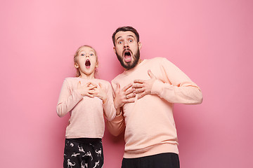 Image showing Surprised young family looking at camera on pink