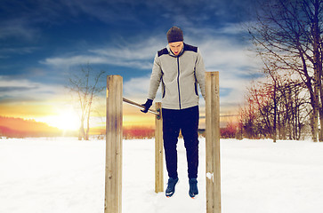 Image showing young man exercising on parallel bars in winter