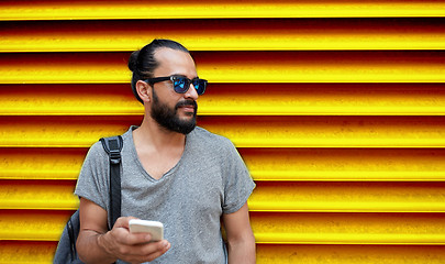 Image showing man in sunglasses with smartphone and bag at wall