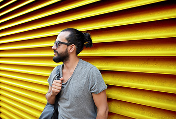 Image showing man in sunglasses with bag standing at street wall