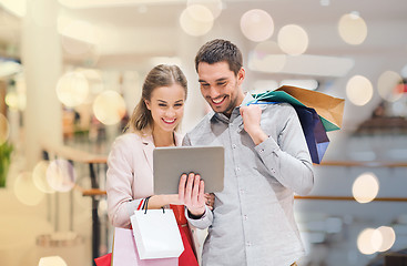 Image showing couple with tablet pc and shopping bags in mall