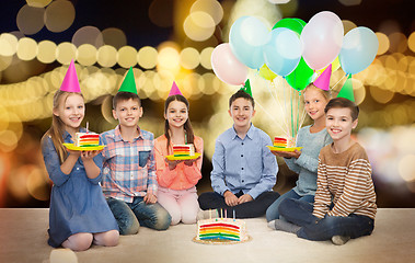 Image showing happy children in party hats with birthday cake