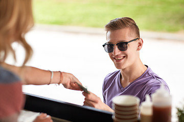 Image showing happy young man paying money at food truck