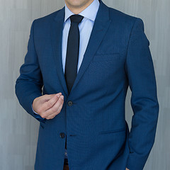 Image showing Torso of a businessman standing, making italian hand gesture, wearing navy blue suit.