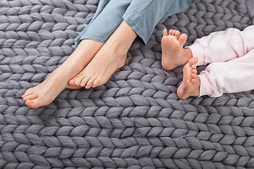 Image showing Mother and daughter legs on woolen knitted plaid
