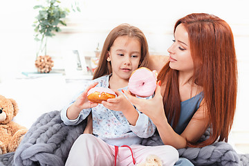 Image showing A little cute girl enjoying, playing and creating with cake with mother