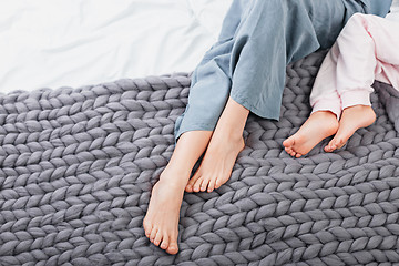 Image showing Mother and daughter legs on woolen knitted plaid