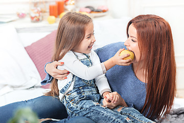 Image showing A little cute girl enjoying, playing and creating with apple with mother