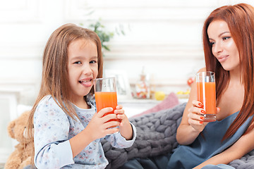 Image showing A little cute girl enjoying, playing and creating with juice with mother