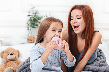 Image showing A little cute girl enjoying, playing and creating with cake with mother
