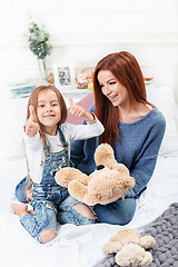 Image showing A little cute girl enjoying, playing and creating with toy with mother