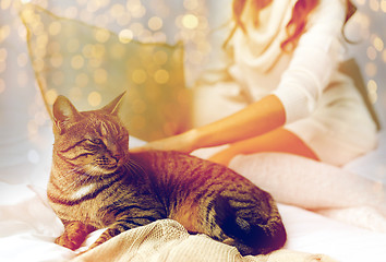 Image showing young woman with cat lying in bed at home