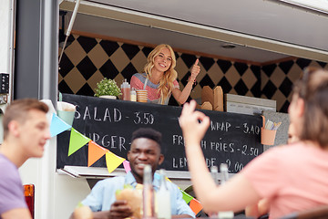 Image showing happy saleswoman showing thumbs up at food truck
