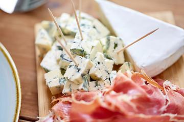 Image showing blue cheese and jamon or parma ham on wooden board