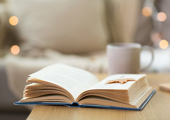 Image showing book with autumn leaf on wooden table at home