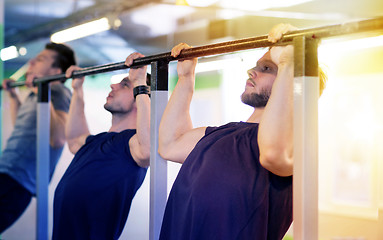 Image showing group of young men doing pull-ups in gym