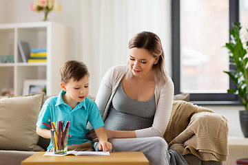 Image showing pregnant mother and son with workbook at home