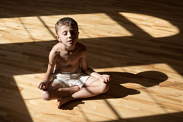 Image showing Charming little boy is while doing yoga at home