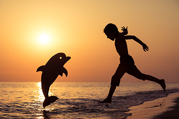 Image showing One happy little boy playing on the beach at the sunset time.