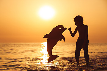 Image showing One happy little boy playing on the beach at the sunset time.