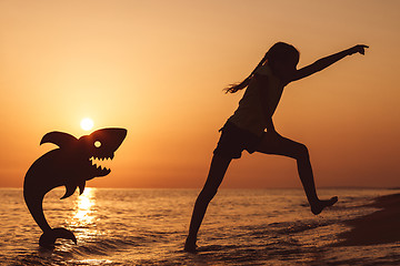 Image showing One happy little girl playing on the beach at the sunset time.