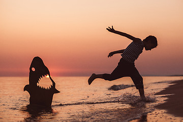 Image showing One happy little boy playing on the beach at the sunset time.