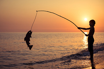 Image showing One happy little boy playing on the beach at the sunset time.