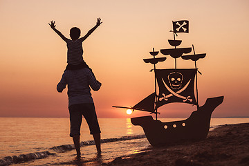 Image showing Father and son  playing on the beach at the sunset time.