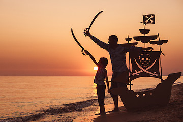 Image showing Father and son  playing on the beach at the sunset time.