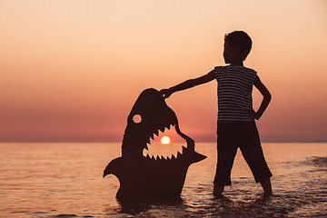 Image showing One happy little boy playing on the beach at the sunset time.