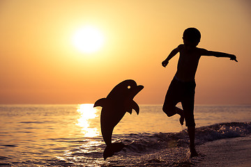 Image showing One happy little boy playing on the beach at the sunset time.