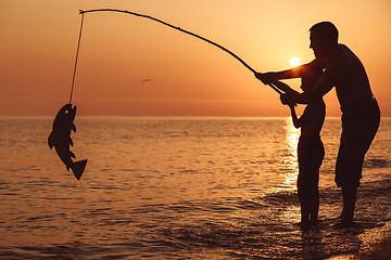 Image showing Father and son  playing on the beach at the sunset time.