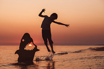 Image showing One happy little boy playing on the beach at the sunset time.