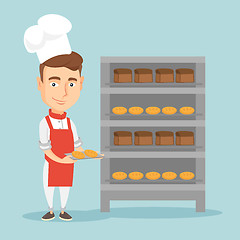 Image showing Happy young male baker holding tray of bread.