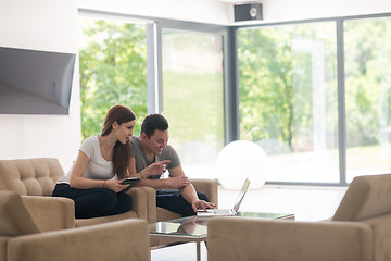 Image showing couple relaxing at  home with tablet and laptop computers