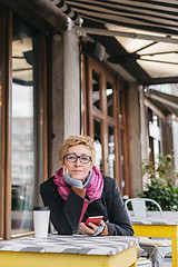 Image showing Dreamy woman with phone in cafe