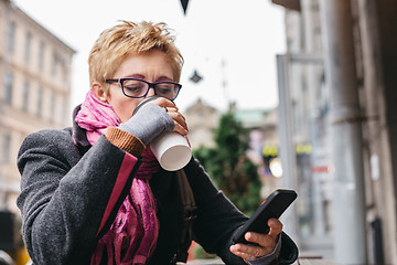 Image showing Woman drinking coffee with smartphone