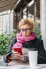 Image showing Smiling woman with phone in cafe