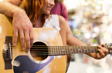 Image showing close up of couple playing guitar over lights