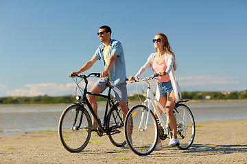 Image showing happy young couple riding bicycles at seaside