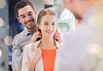 Image showing couple trying golden pendant on at jewelry store