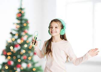 Image showing girl with smartphone and headphones at christmas
