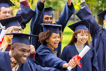 Image showing happy students in mortar boards with diplomas